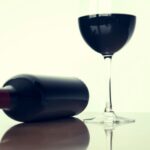 Flaske rødvin og glas rødvin på bord - BetterWine rødvinsudvalg
